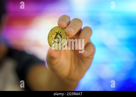 Bitcoin ist die führende Kryptowährung in der Finanzwelt. Bitcoin-Logo auf einer goldenen Münze, die von einer Hand gehalten wird. Stockfoto