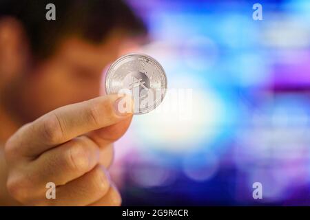 Männer mit einer Cardano-Münze. Logo ADA-Münze, Top-Krypto-Münzen basierend auf der kryptowährung ethereum. Cardano-Logo in einer Silbermünze, die von einem Händler gehalten wird Stockfoto