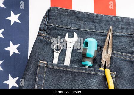 Set von Werkzeugen in Jeans-Tasche auf amerikanischer Flagge Hintergrund. Hintergrundkonzept für den Arbeitstag Stockfoto