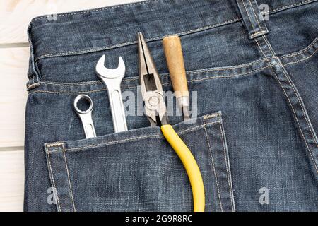 Set von Werkzeugen in der Jeanentasche. Hintergrundkonzept für den Arbeitstag Stockfoto