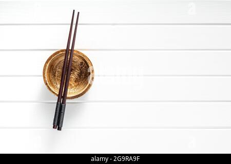 Holzschüssel und Essstäbchen auf weißem Tisch. Draufsicht. Stockfoto