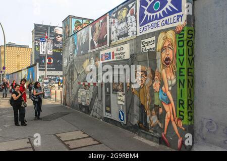 Touristen schauen sich die Zeichnungen an der Berliner Mauer an. Graffiti in der East Side Gallery. Deutschland, München - 28. April 2011 Stockfoto