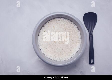 Reis im Reiskocher oder Dampfgarer mit Löffel, Draufsicht Stockfoto