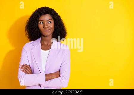 Foto von jungen unglücklichen zweifelhaften afro Frau Blick Copyspace mit gefalteten Armen isoliert auf gelbem Hintergrund Stockfoto