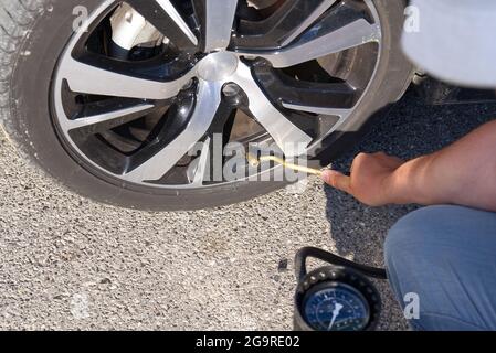 Der Fahrer bläst auf der Tankstelle ein Autorrad auf Stockfoto