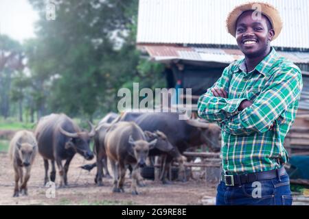 African Farmer mit Hut stehen in der Wasserbüffelfarm.Landwirtschaft oder Anbaukonzept Stockfoto