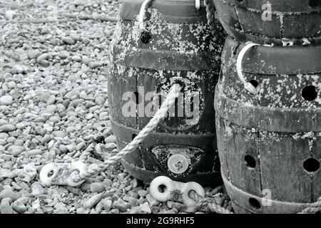 Fischernetze, Hummertöpfe, Ketten und Schwimmwagen verteilen sich um die funktionierenden Trawler am Strand von East Hill, Hastings. Stockfoto