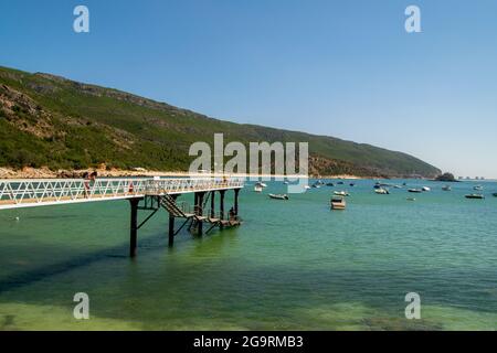 Strandbrücke Portinho da Arrábida in Setúbal, Portugal. Stahlbrücke über den Ozean im Bootshafen. Naturpark Arrábida. Stockfoto