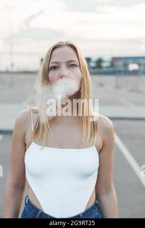 Blonde Frau in der Stadt mit elektronischer Zigarre Vaping Stockfoto