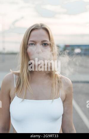 Blonde Frau in der Stadt mit elektronischer Zigarre Vaping Stockfoto