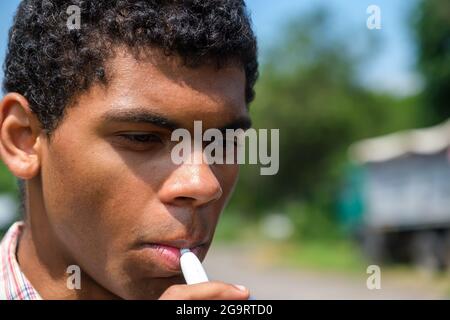 Afroamerikanischer Mann, der im Freien elektronische Zigarette mit E-Flüssigkeit raucht Stockfoto