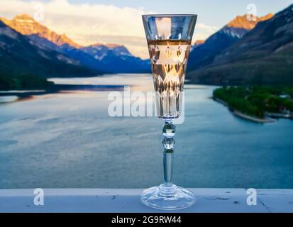 Nahaufnahme eines Kristallflötenglases mit Sekt vor einem wunderschönen Blick auf den Bergsee. Stockfoto