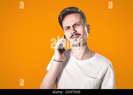 Portrait von Angry verwirrt aggressiv in schlechte Stimmung Kerl gereizt am Telefon spricht auf dem Hintergrund der See Stockfoto