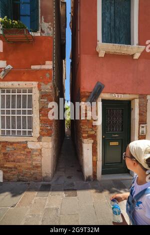 Das Mädchen kommt an Venedig vorbei und blickt auf eine sehr enge venezianische Straße (calle Squero), in der Gegend Dorsoduro Stockfoto