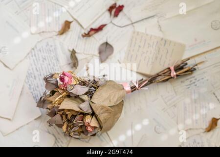 Stapel alter Liebesbriefe, Umschläge und trockener Blumenstrauß, Draufsicht. Nostalgie- und Erinnerungskonzept Stockfoto