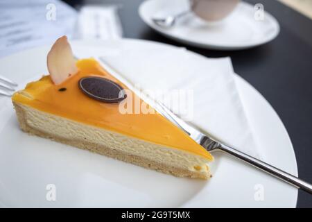 Draufsicht auf den geschnittenen Passionsfrucht-Käsekuchen auf dem schwarzen Tisch. Stockfoto