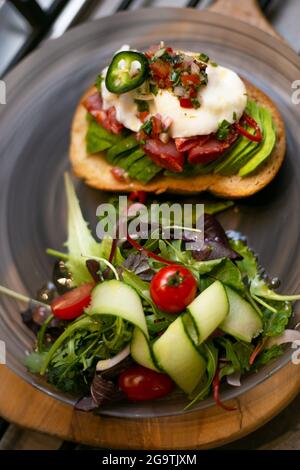 Köstliche selektive Fokus vertikale Aufnahme von Eiern Benedict mit einem leichten Gartensalat auf der Seite Stockfoto
