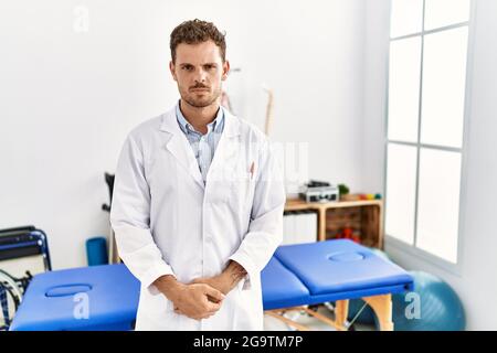 Hübscher junger Mann, der in der Schmerzklinik arbeitet, skeptisch und nervös, runzelnd aufgeregt wegen des Problems. Negative Person. Stockfoto