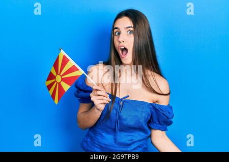 Junge Brünette Teenager mit mazedonischer Flagge erschrocken und erstaunt mit offenem Mund für Überraschung, Unglauben Gesicht Stockfoto