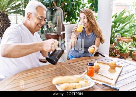 Das hispanische Paar mittleren Alters lächelte und freute sich beim Frühstück auf der Terrasse. Stockfoto