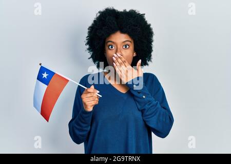 Junge afroamerikanische Frau, die die chilenische Flagge mit der Hand über den Mund hält, schockiert und Angst vor Fehlern. Überraschter Ausdruck Stockfoto
