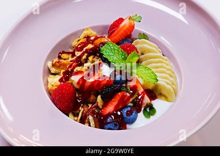 Hausgemachte Müslischale mit Joghurt, Banane und frischen Beeren. Gesundes Frühstückskonzept Stockfoto