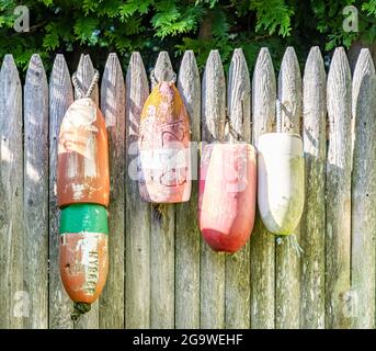 Vier gebrauchte Bojen, die an einem Stockadenzaun hängen Stockfoto