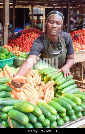 Stock Foto von weiblichen afrikanischen Lebensmittelverkäufer oder Geschäftsfrau mit Schürze, an ihrem Stand in einem Markt, bereit, an Kunden zu verkaufen Stockfoto