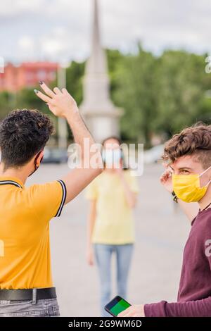 Junge Freunde treffen sich mit sozialer Distanzierung für Coronavirus. Smartphone-Chroma-Taste Stockfoto