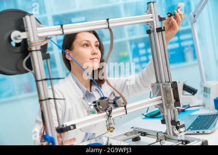 Junge Frau, die mit einem 3d-Drucker arbeitet Stockfoto