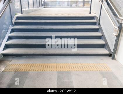 Die moderne Treppe mit dem Metallgeländer in der Fußgängerbrücke zum S-Bahnhof in der Stadt, Vorderansicht für den Kopierraum. Stockfoto