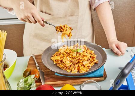 Gekochte Spaghetti Bolognese aus dem Online-Lernen mit digitalem Touchpad Rezept, schmeckt das fertige Gericht Stockfoto