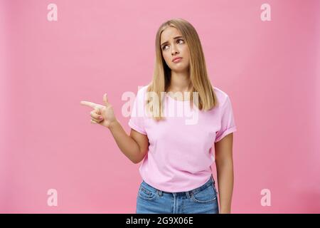 Neid verärgert nette junge europäische Frau mit gebräunter Haut und fair hait kippenden Kopf Anheben Augenbrauen in traurigen dummen Blick zeigt, Blick nach links mit Bedauern Stockfoto