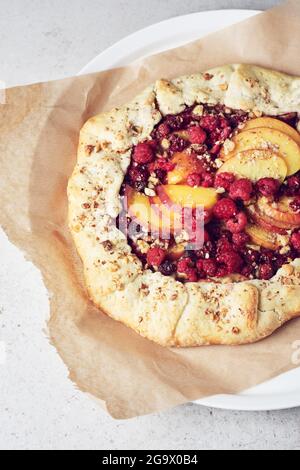 Himbeer- und Pfirsich-Torte, offener Kuchen auf hellem Hintergrund. Stockfoto