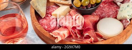 Rosenwein mit Wurstwaren und Käseplatte Panorama. Italienische Antipasti-Panorama-Banner mit Weinglas und Schinken aus Parma, Salami, Gorgonzola Stockfoto