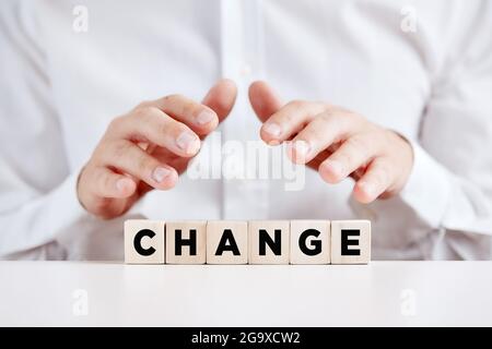 Geschäftsmann hält seine Hände mit dem Wortwechsel schützend über die Holzwürfel. Change Management im Business oder ein sich veränderndes Lifestyle-Konzept. Stockfoto