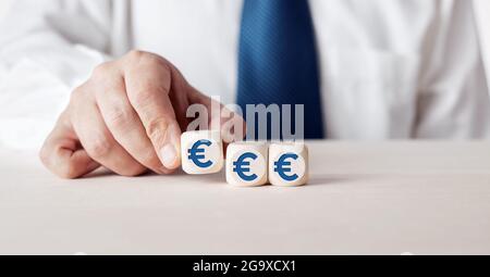 Geschäftsmann arrangiert Holzwürfel mit Euro-Währungssymbol. Business Finance-Konzept. Stockfoto