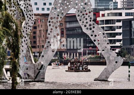 Berlin, Deutschland. Juli 2021. An einem warmen Sommerabend segelt ein kleines Boot entlang der Spree zu Füßen der Monumetalskulptur 'Molecule man'. Quelle: Stefan Jaitner/dpa/Alamy Live News Stockfoto