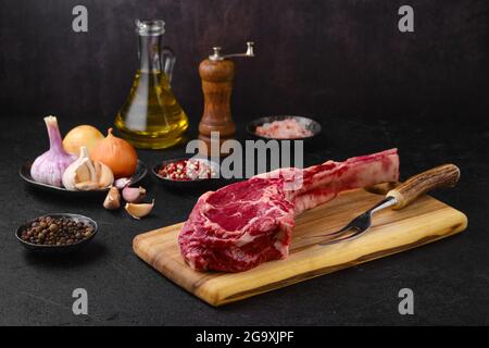 Rohes Rind-Cowboy-Steak mit Gewürzen und Gewürzen zum Kochen bereit Stockfoto