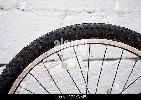 Nahaufnahme eines Fahrradrades mit weißem Steinwand-Hintergrund. Stockfoto