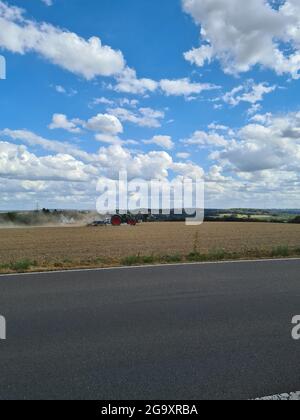 Moderner roter Traktor, der direkt in den Stoppeln sät, mit roter Ausrüstung und GPS für die Präzisionslandwirtschaft auf den Feldern Stockfoto