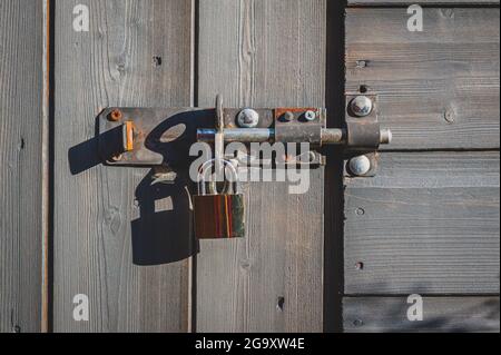 Messing-Vorhängeschloss mit Schraubverschluss an Holztür. Stockfoto