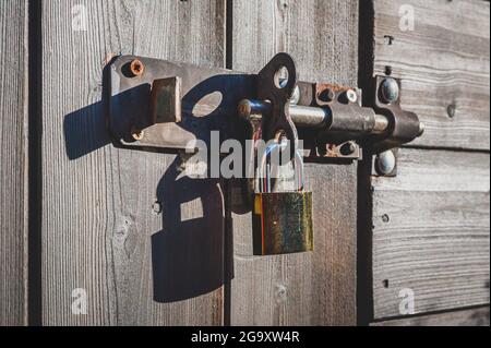 Messing-Vorhängeschloss mit Schraubverschluss an Holztür. Stockfoto