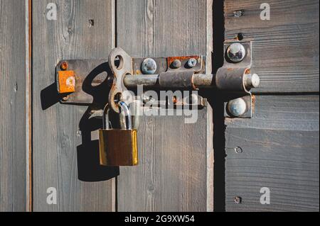Messing-Vorhängeschloss mit Schraubverschluss an Holztür. Stockfoto