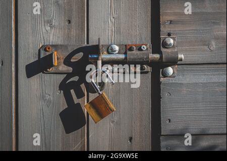 Messing-Vorhängeschloss mit Schraubverschluss an Holztür. Stockfoto