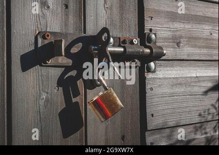 Messing-Vorhängeschloss mit Schraubverschluss an Holztür. Stockfoto