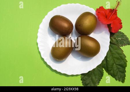 Kiwifruit süße Tannine Frucht gilt als Superfood mit Nährstoffen. Frische Bio-Kiwi-Früchte auf weißem Teller mit grünem ackground, verziert mit Flow Stockfoto