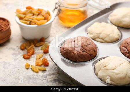 Backform mit rohen Muffins und Zutaten auf hellem Hintergrund Stockfoto