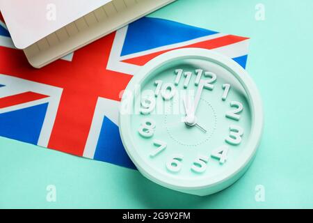 Uhr und UK-Flagge auf farbigem Hintergrund. Zeit, Englisch zu lernen Stockfoto