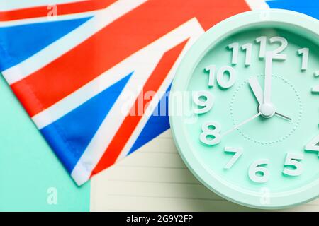 Notizbuch, Uhr und UK-Flagge auf farbigem Hintergrund, Nahaufnahme. Zeit, Englisch zu lernen Stockfoto
